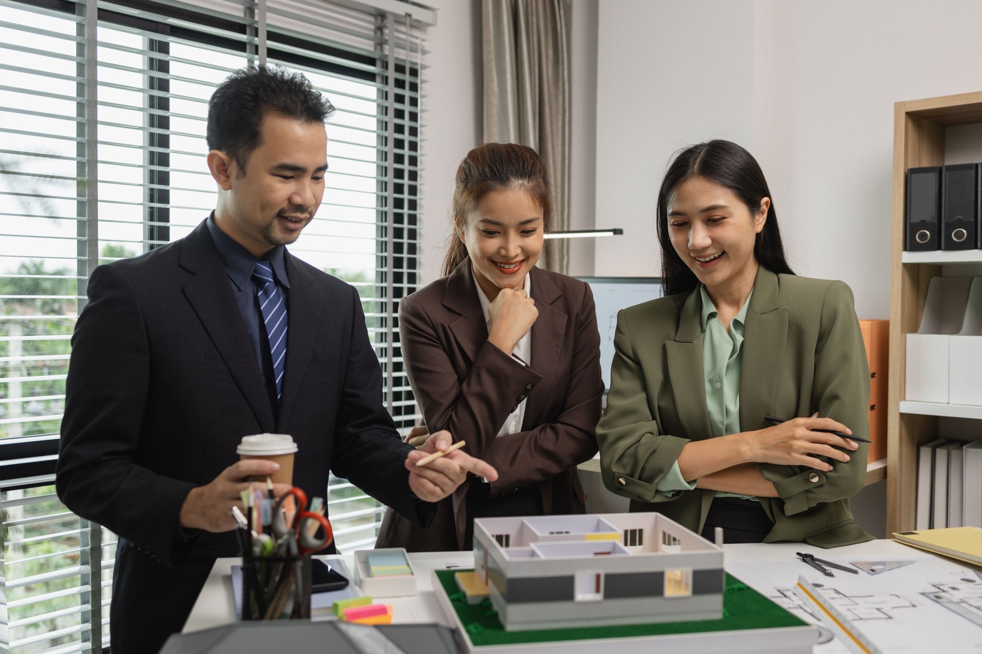 Architects work with engineers and contractors in the office to check the accuracy of the first draft plan, blueprint on the desk, three architects are working together in the workplace